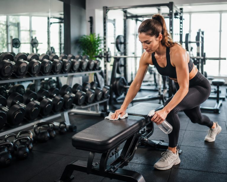 organized dumbbells and equipment, athlete cleaning workout bench after exercise, respectful fitness culture concept